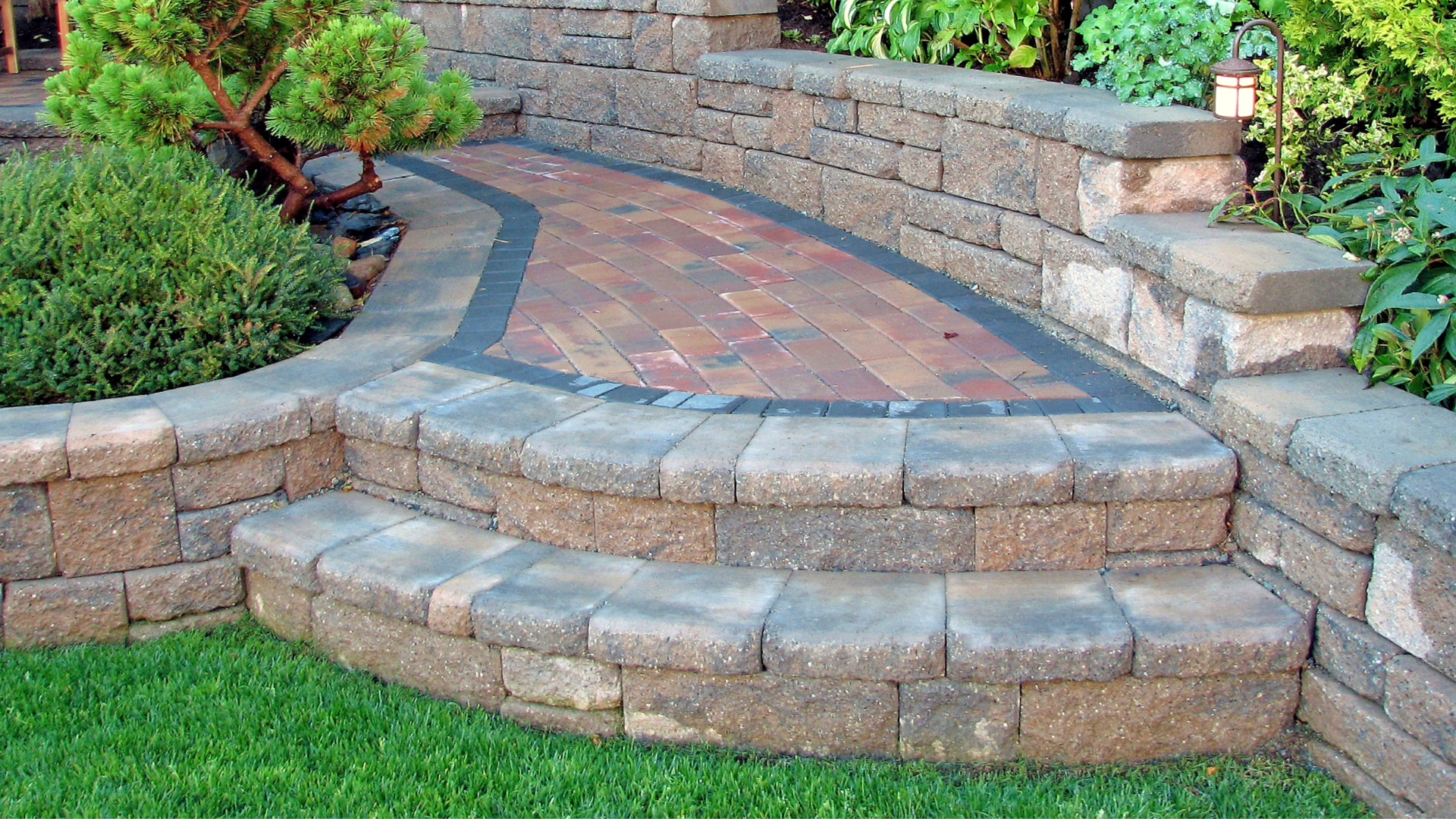 a stone wall with steps leading up to a brick walkway