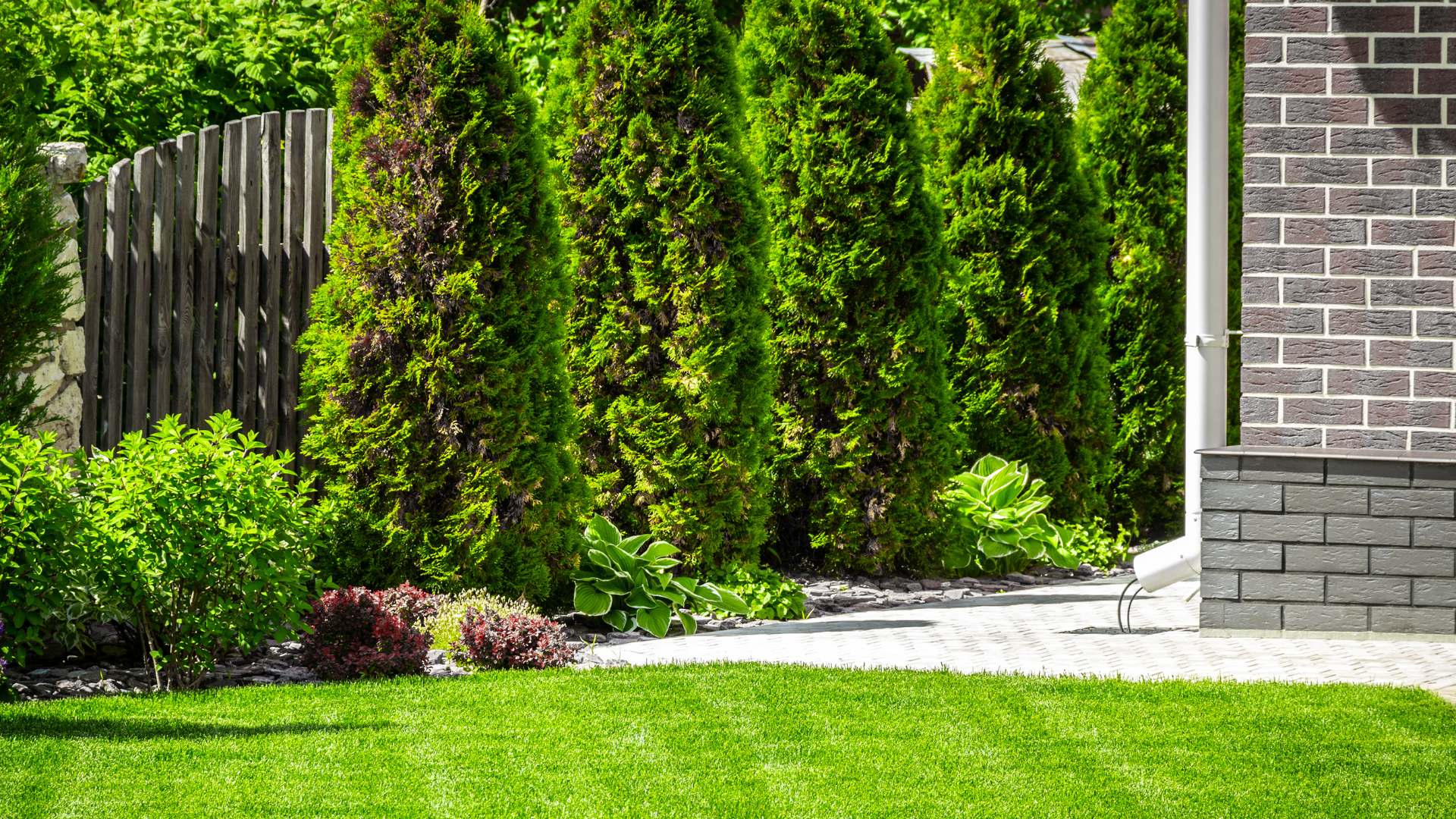 a brick house with a lush green lawn and trees in front of it .